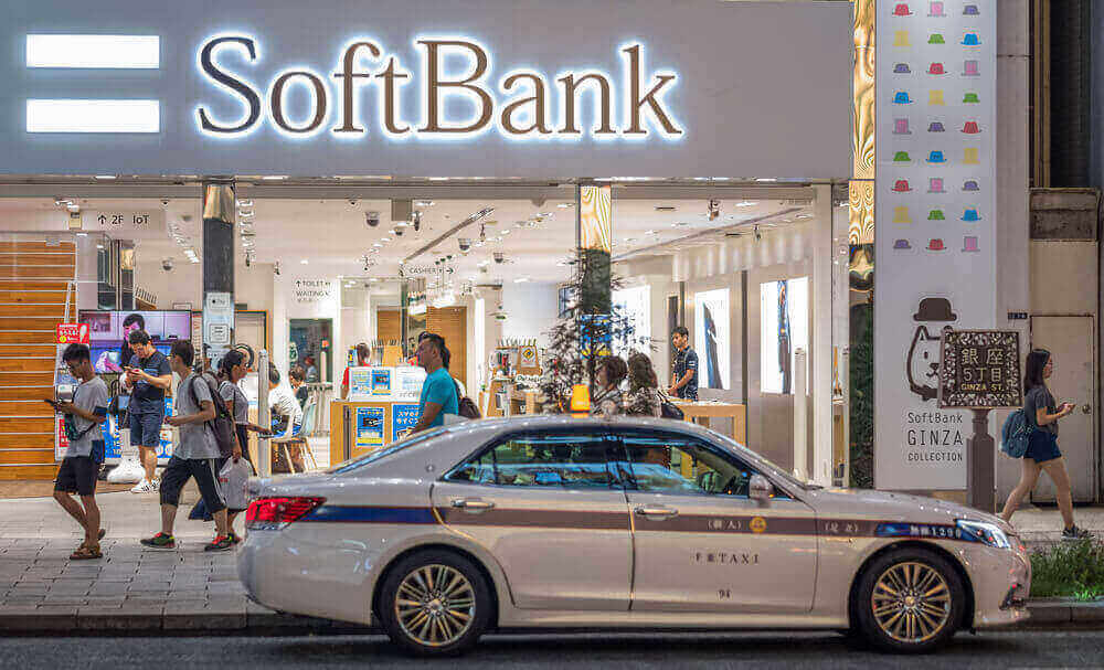 a softbank branch with people walking in front of it and a car parked