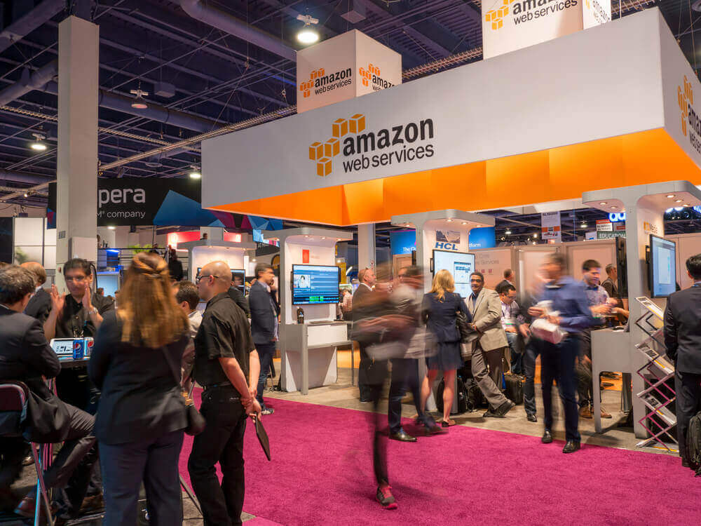 people passing by and staying at the Amazon Web Services booth in an exhibitrion