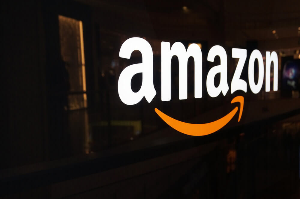 The Amazon logo shown on a shiny black wall
