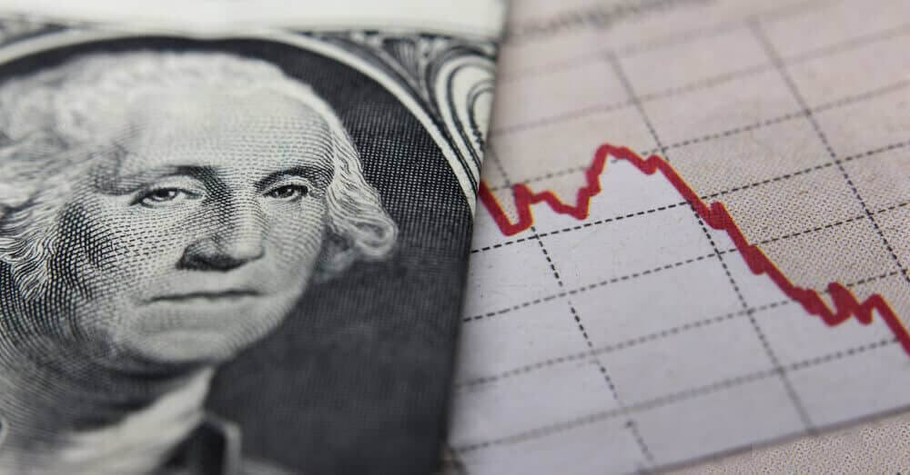 a folded dollar bill and a chart on the background indicating a drop