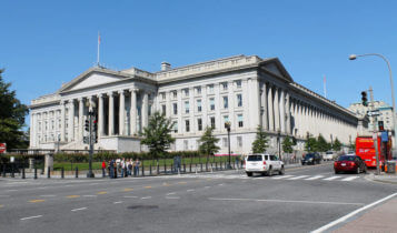 the building of the US department of the treasury with cars on the road passing by