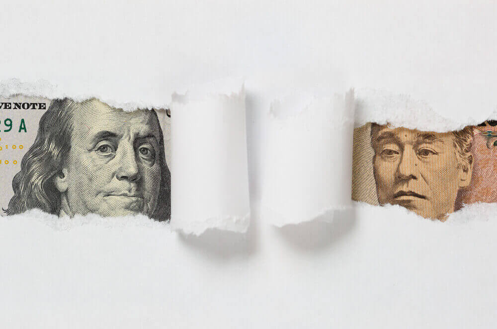 White paper ripped to show dollar and yen paper bills