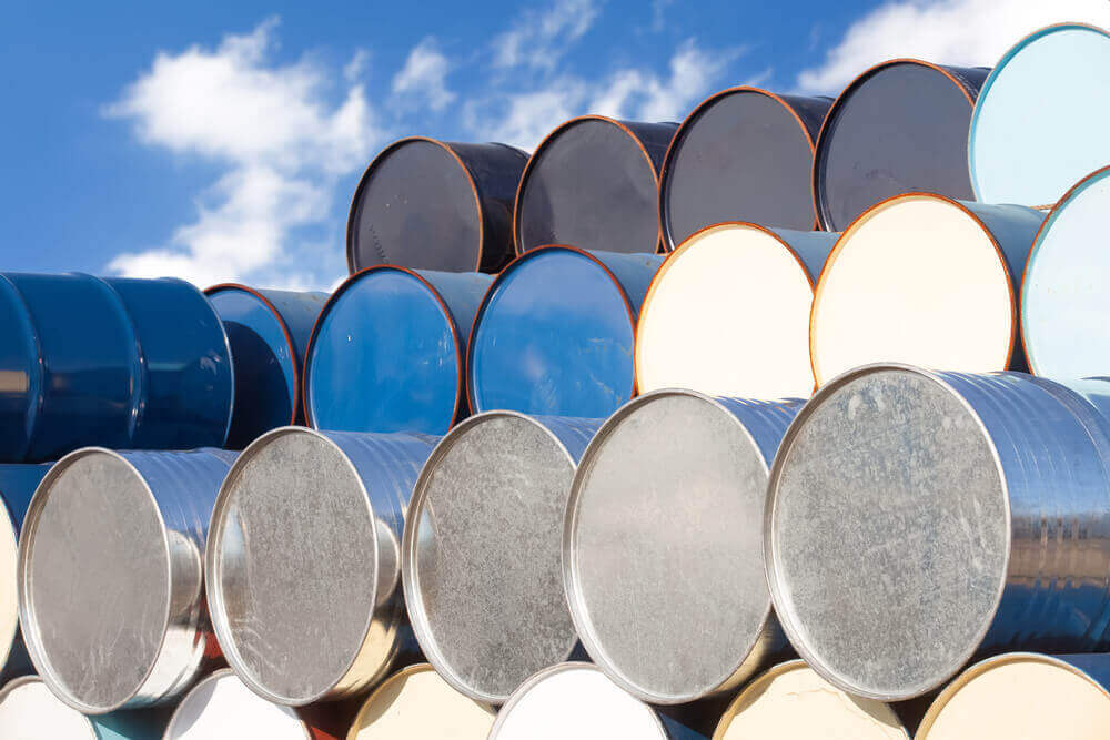 blue oil barrels are stacked on top of each other with a blue sky background