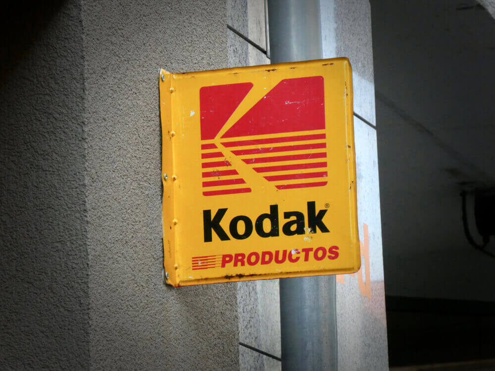 a yellow sign with the kodak logo attached to a wall