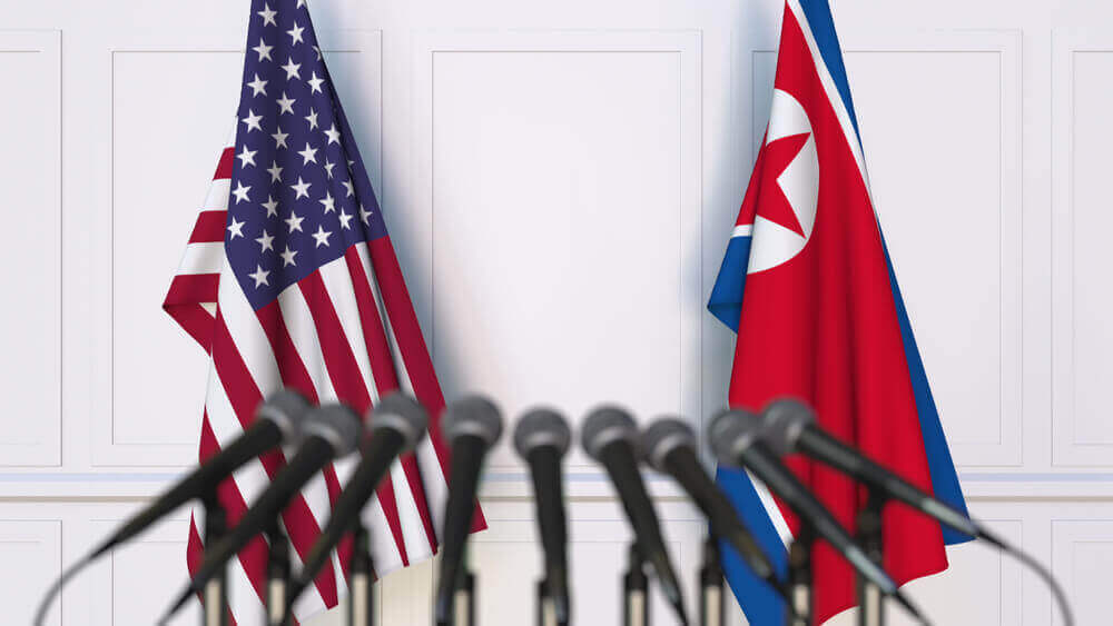 flag of USA beside the flag of North Korea with several microphones in front
