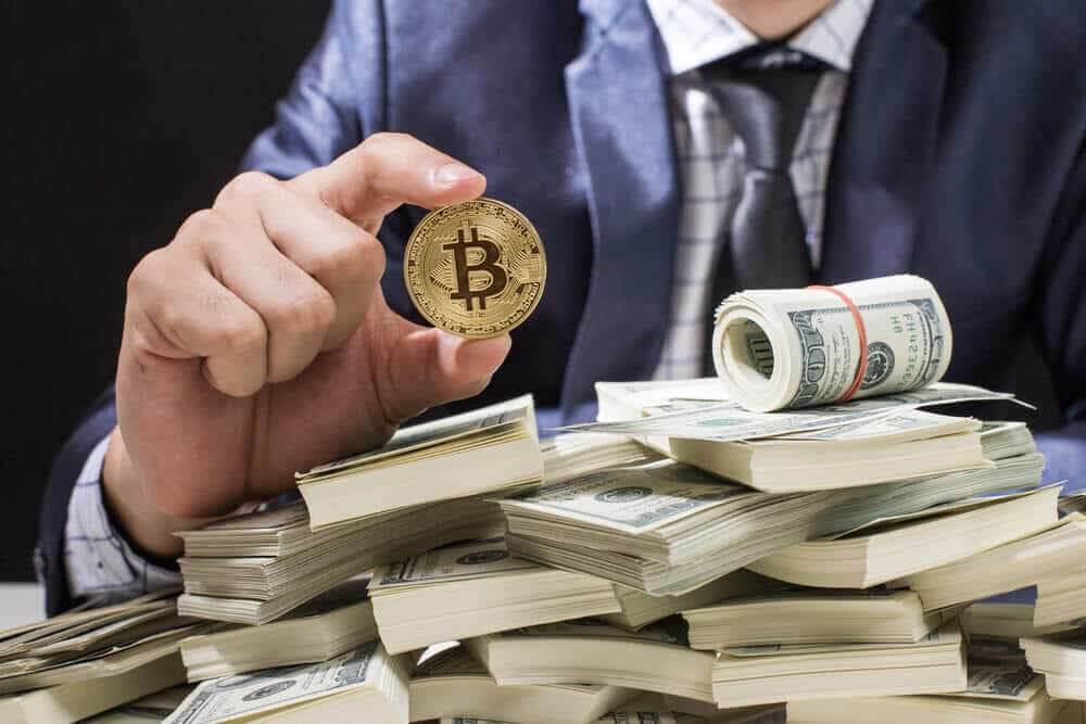 Bitcoin, a business man holding a bitcoin coin and a pile of cash below the coin.