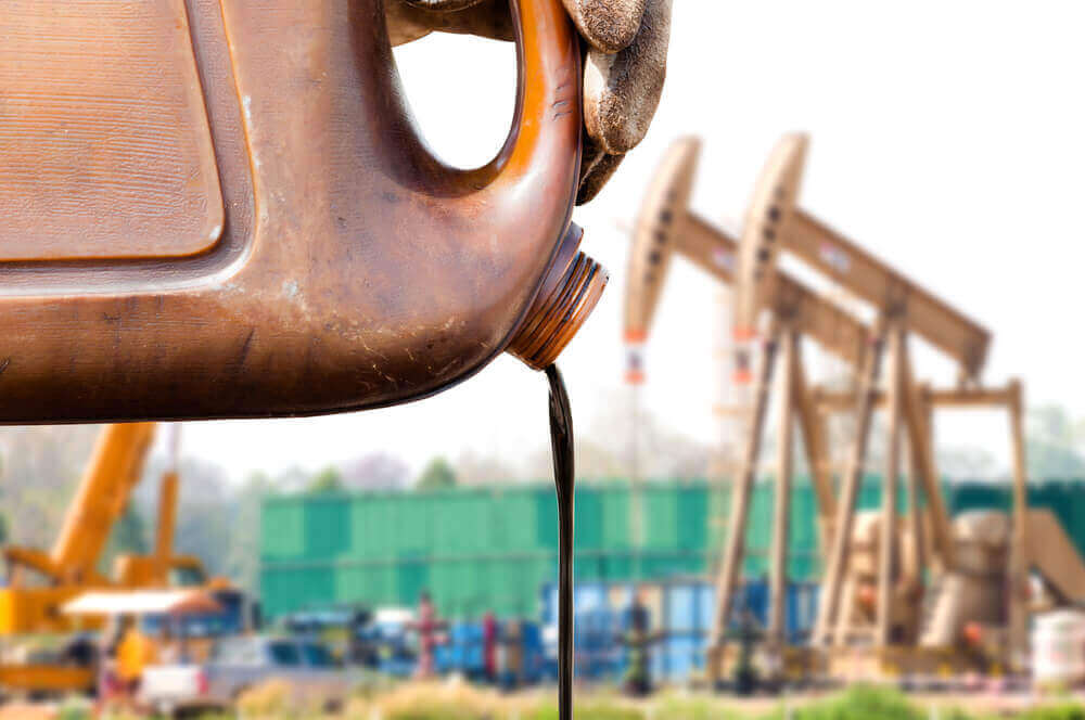 crude oil coming out from a can with oil pump jacks on the background