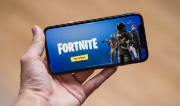 a fortnite screen is being show on a smartphone that is being held by a hand