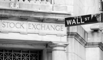 Bolsa de Valores- Uma foto mostrando a placa de rua de Wall Street do lado de fora de um prédio com "Bolsa de Valores" escrito na fachada_Finance Brokerage (Corretagem Financeira)