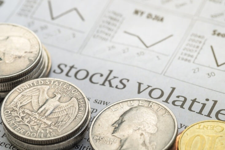 Finance Brokerage-Share Market: stock volatility concept, various coins on top of a paper with “stocks volatile” written on it 