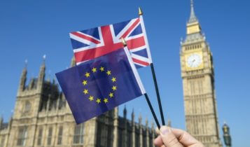 Finance Brokerage-Trade Agreement: hand waving mini flags of the UK and EU with the British Parliament and Big Ben on the background