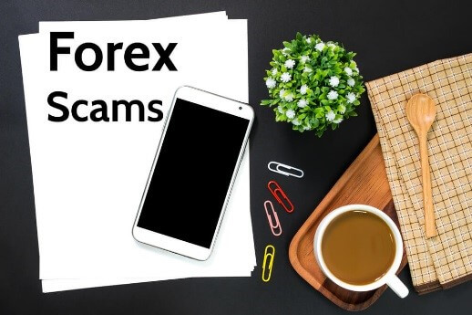 The picture displays a paper with the phrase “Forex Scams” written on it with a smartphone, paper clips, a plant, and a cup of coffee. – Finance brokerage The picture displays a paper with the phrase “Forex Scams” written on it with a smartphone, paper clips, a plant, and a cup of coffee. – Finance brokerage
