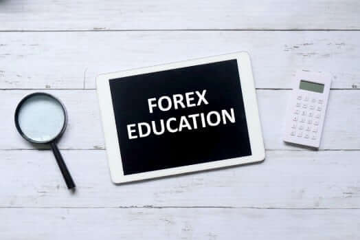 Top view of magnifying glass, calculator, and a tablet with a “Forex Education” sentence written – Finance Brokerage