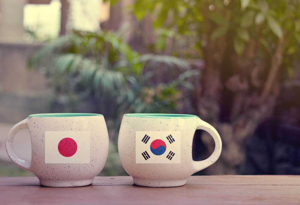 Parliament: Japan and South Korea Flag on two tea cups with blurry background