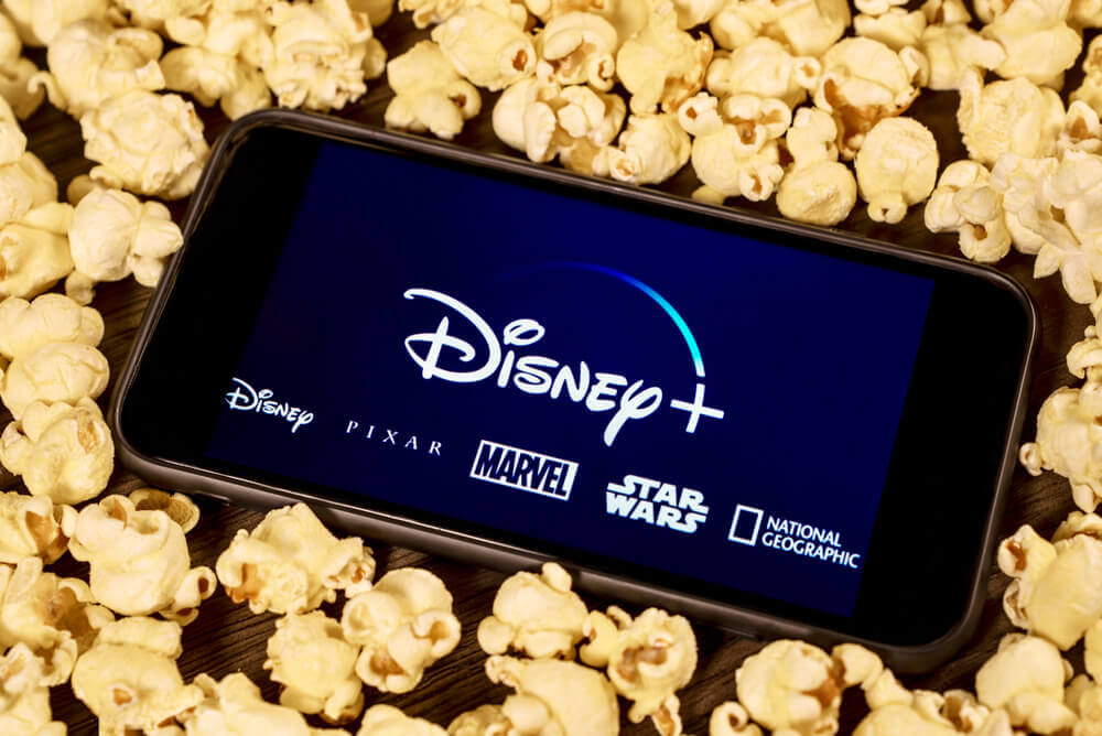 Walt Disney: Disney Plus on the smartphone with popcorn.
