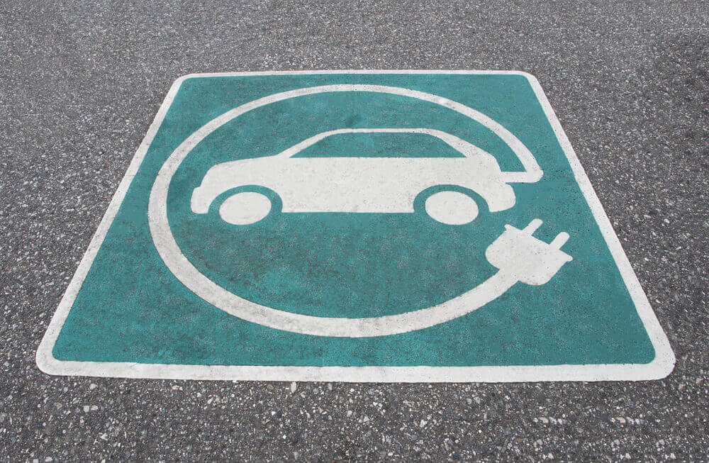 Charging Stations: Electric vehicle charging station sign on asphalt in public area.