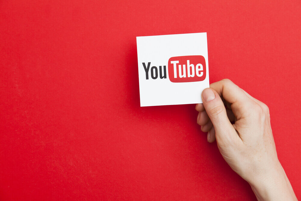 YouTube: Hand holding YouTube logo with a red background.