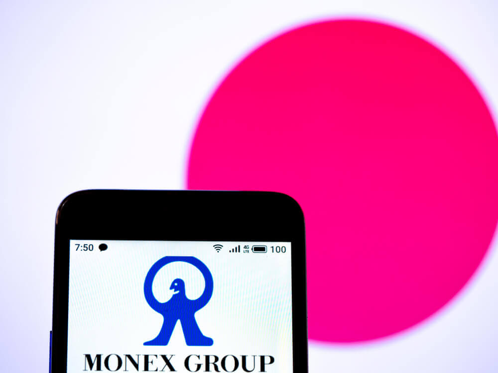 The Monex Group logo on a screen with the Japanese flag in the background.
