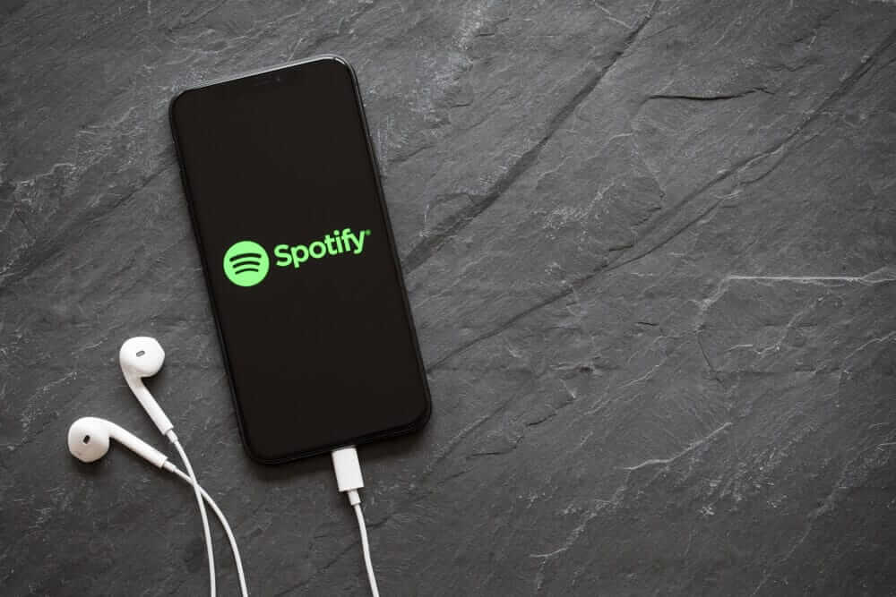 A latest generation iPhone with a Spotify logo on its screen.