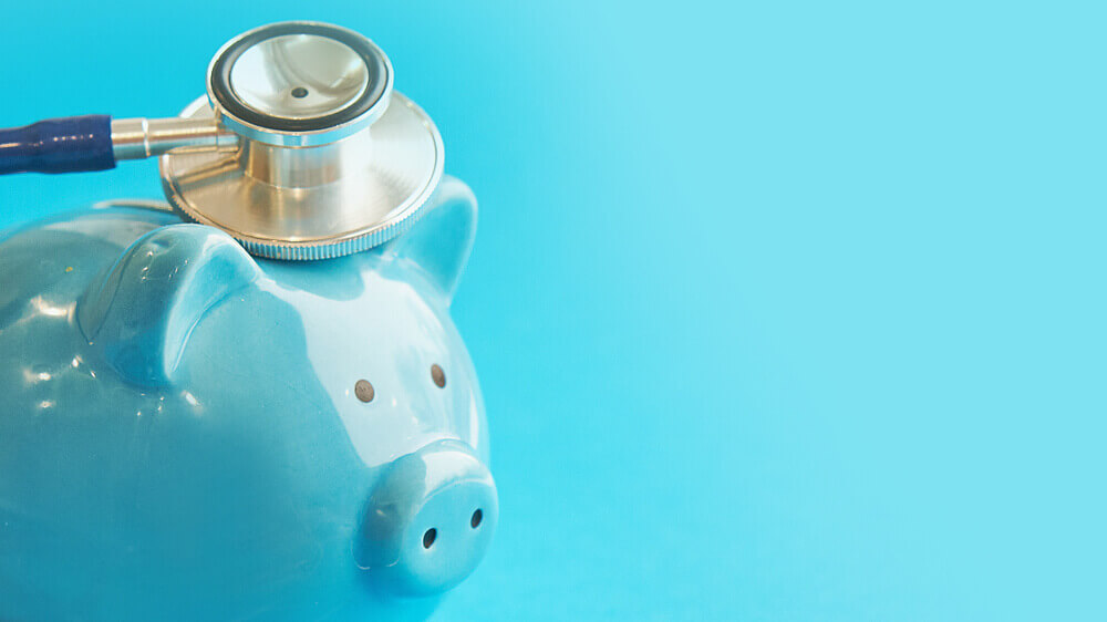 Piggy bank with stethoscope isolated on blue background.