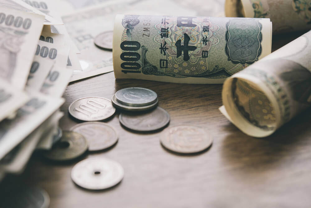 Closeup of Japanese yen money bills and coins on wood table background.
