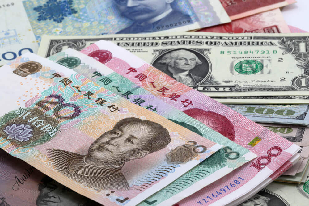 China yuan stack over US dollar bill.
