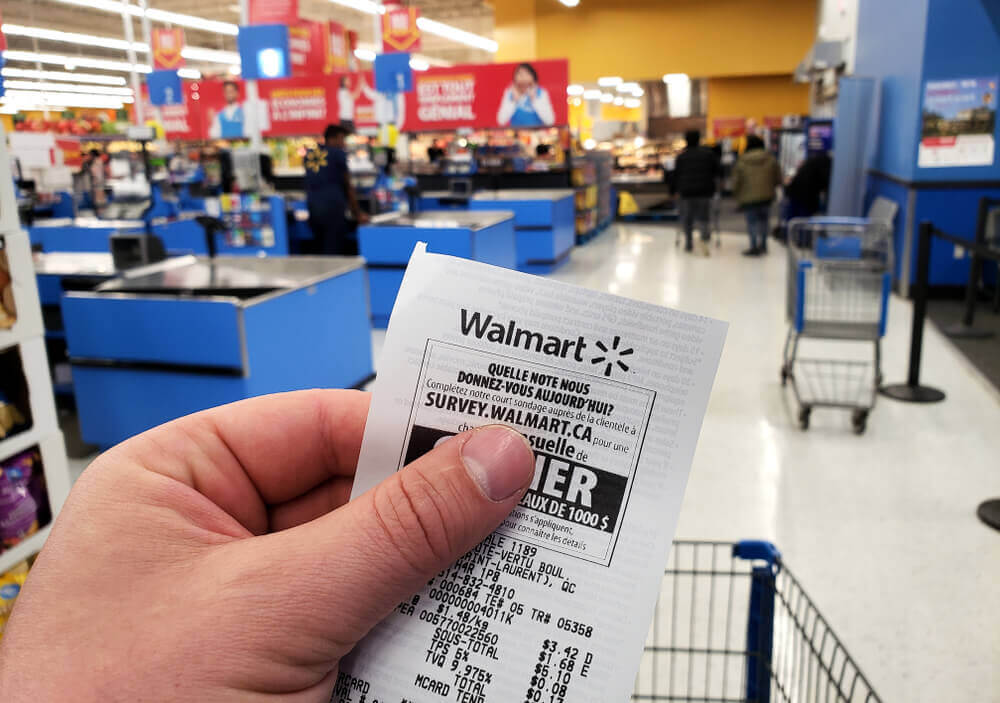 A hand holding a Walmart receipt in Walmart store.