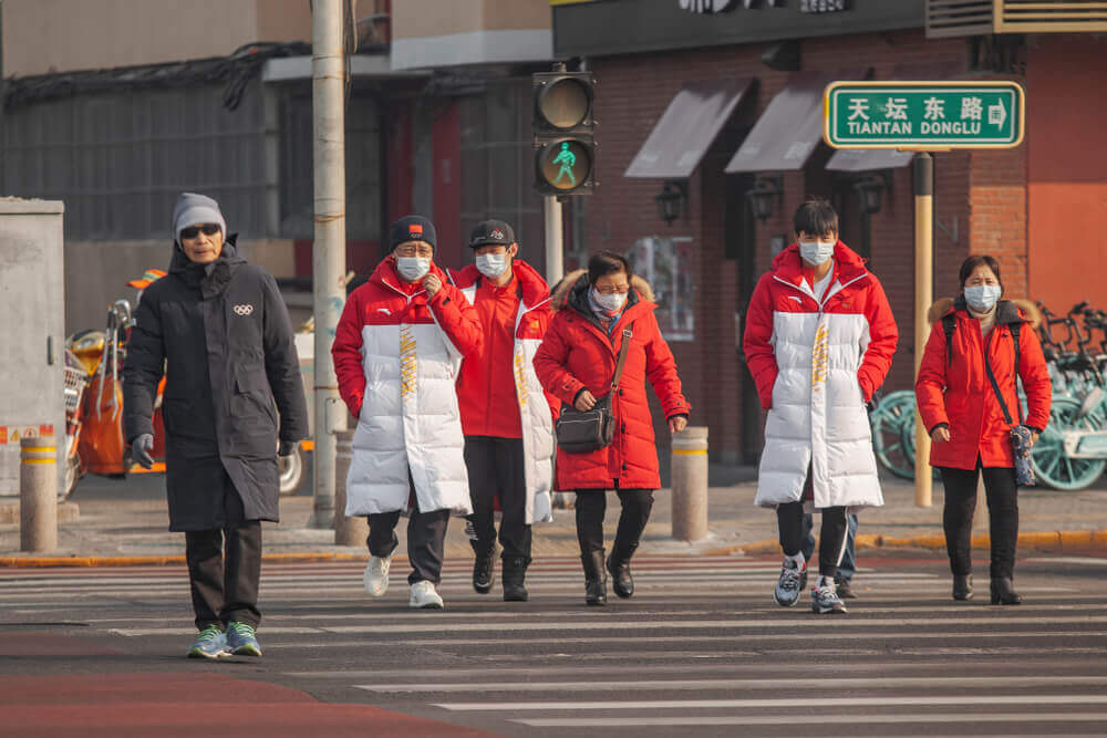 chinese pedestrians walking in the street wearing breathing masks.