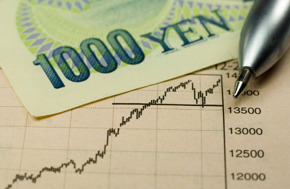 1000 Yen banknote with pen and rising stock chart.