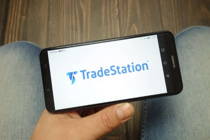 hombre sujetando un teléfono inteligente con el logotipo de Tradestation