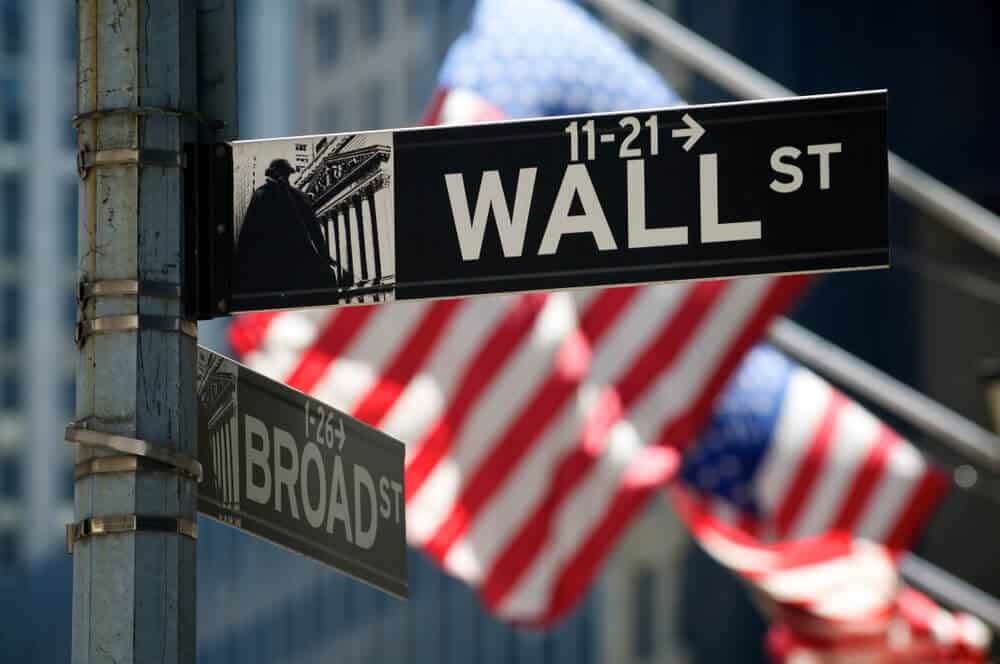 American flags fly behind a sign for Wall Street.