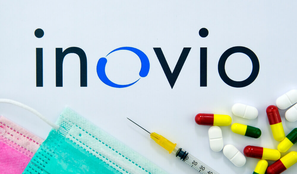 Inovio Pharmaceuticals logo on the brochure, pills, syringe and viral masks. Flat lay.
