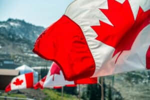 Canada flags waving at the wind in a mountain scenario.