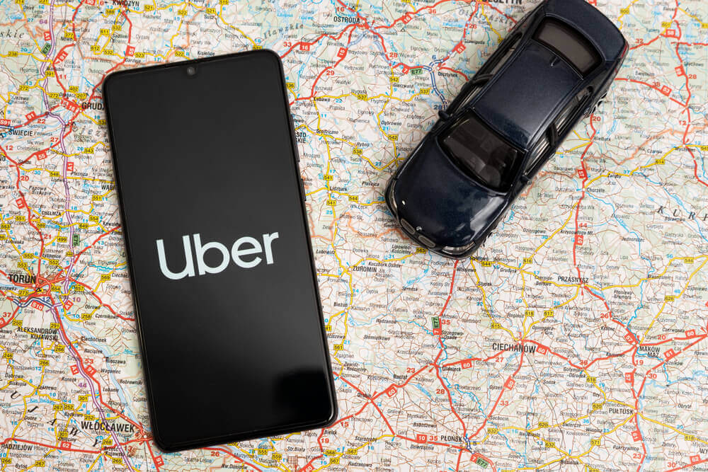 Uber logo on smartphone with map background.