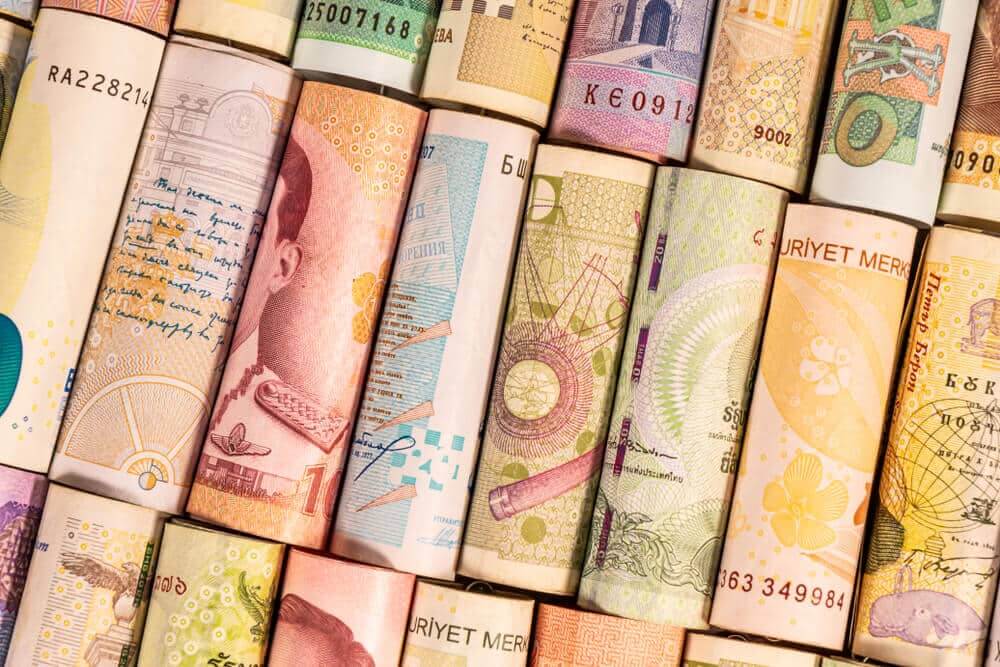 Different colourful banknotes from various countries on rolls.