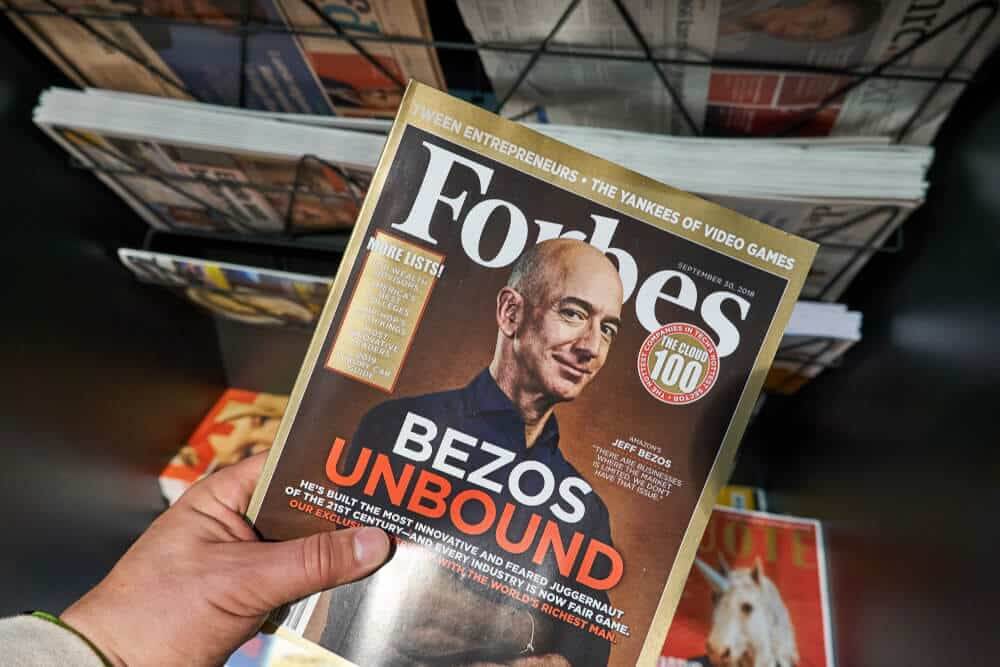 Forbes magazine with Jeff Bezos on the cover in a hand.