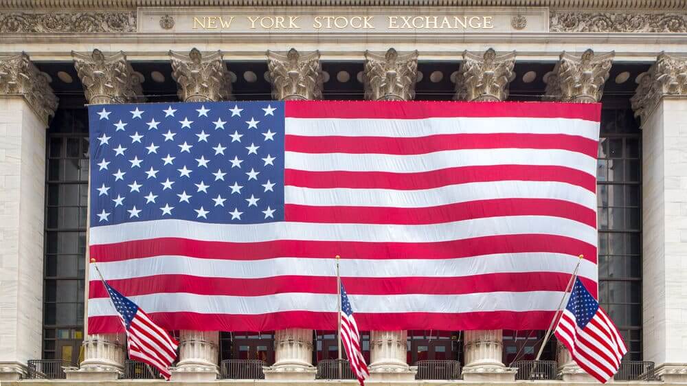 The New York Stock Exchange draped with a large American flag on Wall Street.