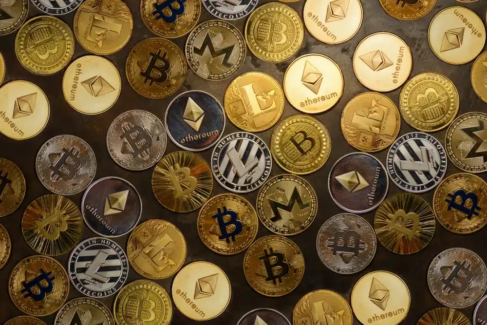 Descrição da imagem: Uma representação visual de uma moeda de Bitcoin, símbolo da criptomoeda, em primeiro plano. A moeda é dourada e apresenta o logotipo do Bitcoin, um "B" maiúsculo com duas linhas verticais atravessando-o, imitando um símbolo de moeda. O fundo é desfocado, com tons suaves e modernos, sugerindo tecnologia e inovação financeira. Esta imagem é utilizada em um site financeiro para representar o mercado de criptomoedas e o investimento em Bitcoin.